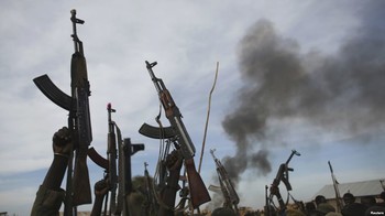 File photo: Rebel fighters hold up their rifles as they walk in front of a bushfire in a rebel-controlled territory in Upper Nile state, South Sudan Feb. 13, 2014.