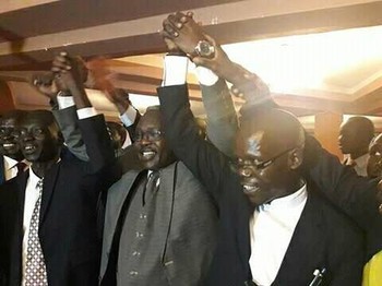 File photo: Minster Martin Elia (middle) and opposition officials hold their hands up after signing the peace agreement in Kampala. (Radio Tamazuj)