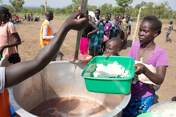 File photo: A woman being served a hot, fortified maize meal with beans to share with her children at Bidi bidi camp in Uganda. (WFP/Henry Bongyereirwe)