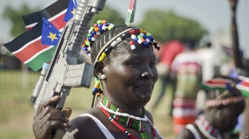 File photo: A South Sudanese woman wears the national flag and carries a mock gun as she attends an Independence Day ceremony in Juba, July 9, 2015. (VOA)