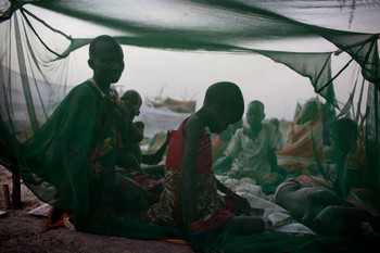 File photo: A mother camps outside with her children under a mosquito net at an emergency food distribution site being run by UNICEF and the World Food Programme (WFP) in Thanyang, Unity State.( UNICEF/Kate Holt)