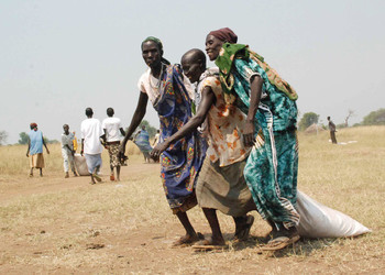 File photo: South Sudanese women drag bags of grain to a central collection point dropped by WFP (IRIN)