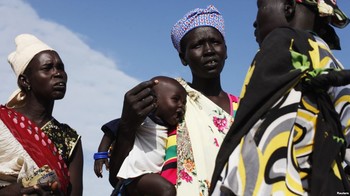 File photo: A woman carries a baby as she talks with other women talk at a food distribution center in Minkaman, Lakes State, South Sudan, June 27, 2014. (VOA)