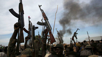 File photo: Rebel fighters hold up their rifles as they walk in front of a bushfire in a rebel-controlled territory in Upper Nile state, South Sudan Feb. 13, 2014.