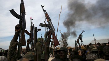 FILE - Rebel fighters hold up their rifles as they walk in front of a bushfire in a rebel-controlled territory in Upper Nile state, South Sudan Feb. 13, 2014.