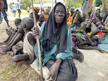 A blind woman displaced by floods sits and waits with a group of children while others cook in Duk County, Jonglei, South Sudan, 24 September 2020. [Photo: OCHA/Anthony John Burke]