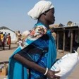 Photo: South Sudanese mother carries a bag of cereals provided by the WFP in in El Alagaya refugee camp in White Nile state (Ala Kheir/WFP)
