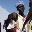 File photo: A woman carries a baby as she talks with other women talk at a food distribution center in Minkaman, Lakes State, South Sudan, June 27, 2014. (VOA)