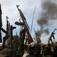 FILE - Rebel fighters hold up their rifles as they walk in front of a bushfire in a rebel-controlled territory in Upper Nile state, South Sudan Feb. 13, 2014.